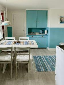 a kitchen with blue cabinets and a table and chairs at Traditional Red House By The Lake In Småland in Åby