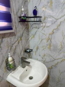 a white sink in a bathroom with a marble wall at Max Court in Ikeja