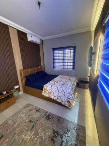a bedroom with a blue bed and a window at Max Court in Ikeja