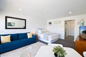 a living room with a blue couch and a bed at Bay View - Ocean Nest in Lorne