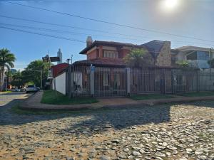 a house with a fence in front of a street at Esquina Mburucuya in Asunción