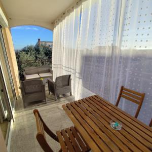 un balcone con tavolo e sedie in legno e una finestra. di Apartman Ema a Tar