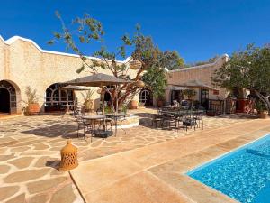 a patio with tables and chairs and a swimming pool at Palais Tiyana in Al Ghar