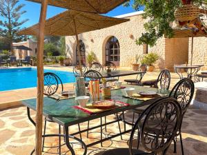 a table with chairs and an umbrella next to a pool at Palais Tiyana in Al Ghar