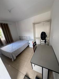 a bedroom with a bed and a desk and a table at Família Ebeneze in Nova Friburgo