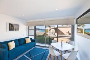 a living room with a blue couch and a table and chairs at Bay View Ocean Views in Lorne