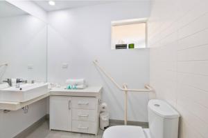 a white bathroom with a sink and a toilet at Bay View Ocean Views in Lorne