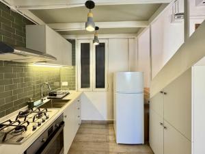 a kitchen with a white refrigerator and a sink at The Square House - Berbara in Al Ḩulwah