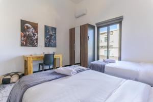 Residence 4 - Comfy Apts & Balconies in Mar Mikhael في Al Mudawwar: سريرين في غرفة مع مكتب وكرسي