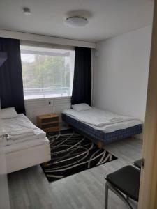 twee bedden in een kamer met een raam en een tapijt bij Kotimaailma - Valoisa ja tilava neliö in Turku