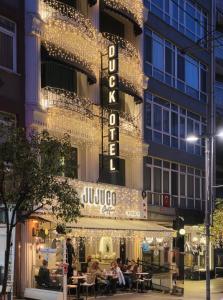 Personas sentadas afuera de un hotel por la noche en Duck Otel, en Estambul