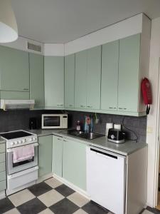 een keuken met witte kasten en een geblokte vloer bij Kotimaailma - Valoisa ja tilava neliö in Turku