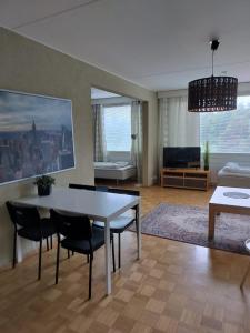 een woonkamer met een tafel, stoelen en een bank bij Kotimaailma - Valoisa ja tilava neliö in Turku