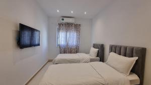 una camera da letto con due letti e una TV a parete di Confort & Soleil Akid Lotfi a Orano
