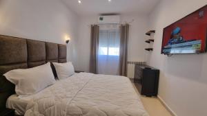 una camera da letto con un letto e una TV a parete di Confort & Soleil Akid Lotfi a Orano Altre 7 foto