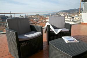 2 sedie e un libro seduti su un balcone di Residence Le Terrazze a Trieste