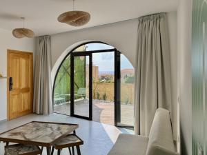 a living room with a table and a large window at Butterwave | 1BR Jacuzzi & Terrace in Kfar Aabida in Fad‘ūs
