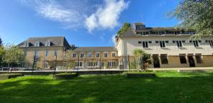 a large building with a green lawn in front of it at Cosy Er Lann Gîte Cèdre in Val Couesnon