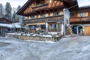 een groot houten gebouw met sneeuw ervoor bij Ferienwohnung Höllental in Grainau