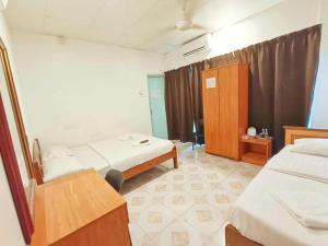 a bedroom with two beds and a wooden cabinet at Hotel Western in Sandakan +8 photos
