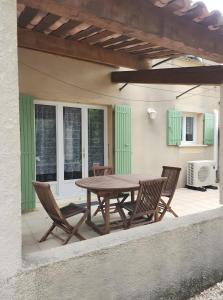 Una mesa y sillas de madera en un patio. en Gite Le Roma, en Oppède