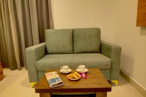 a living room with a green chair and a coffee table at Fly Inn Bangalore Airport in Muthugadahalli