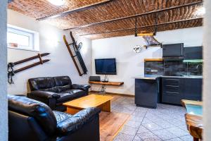 a living room with leather furniture and a kitchen at Apartman Kamzik - 2 in Veľká Lomnica