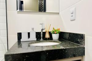 a bathroom sink with a black counter top at Studio Citrino – Localização perfeita próx. da Ufu in Uberlândia +26 photos