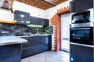 a kitchen with black appliances and a brick wall at Apartman Kamzik - 2 in Veľká Lomnica
