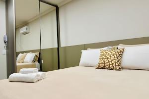 a bedroom with a large bed with a mirror at Studio Citrino – Localização perfeita próx. da Ufu in Uberlândia