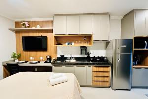 a kitchen with white cabinets and a stainless steel refrigerator at Studio Citrino – Localização perfeita próx. da Ufu in Uberlândia