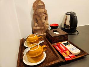 een tafel met drie theepotten op een dienblad met een beeld bij Paradise K Forest Hotel in Siem Reap