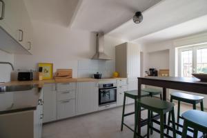 a kitchen with white cabinets and green bar stools at Casa all'angolo in Rocchetta Tanaro +48 photos