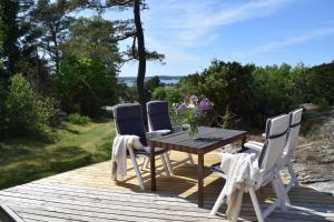 Private holiday home near the sea SE09157 في Spekeröd: سطح خشبي مع طاولة وأربع كراسي