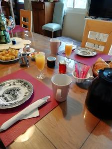 a wooden table with plates and glasses of orange juice at Chambre d'Hotes La Roseraie in Parsac