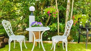 a table with two chairs and a table with flowers at Bansuan poordee บ้านสวนพอดี in Hat Yai