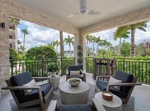 a patio with chairs and tables and a balcony with palm trees at Stylish Downtown Naples Retreat in Naples