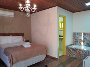 a bedroom with a bed and a chandelier and a tub at Recanto dos Açores in Florianópolis