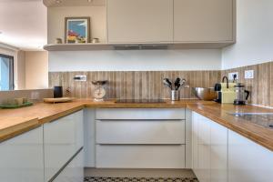 villa California - Villa d'exception avec vue mer panoramique - Veules-les-Roses في فول-لي-روز: مطبخ مع خزائن بيضاء وقمم منضدة خشبية