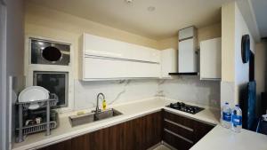 uma cozinha com armários brancos e uma pia em Gold Crest Lahore - Guest Nest Luxury Stays em Lahore