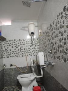a bathroom with a toilet and a wall with tiles at Manvitha Homestay in New Hampi