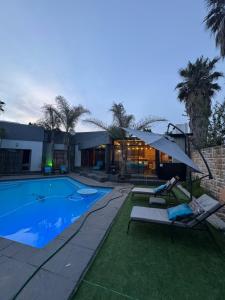 バンダービールパークにあるZee Lifestyle Guesthouseのラウンジチェア2脚付きのスイミングプール、家