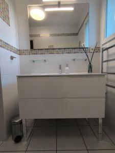 een witte badkamer met een wastafel en een spiegel bij La Parenthèse colorée in Châteaumur +30 foto's