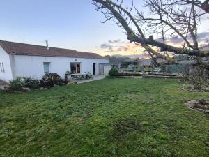 een tuin met een wit huis en een grasveld bij La Parenthèse colorée in Châteaumur