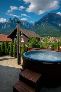 una bañera de hidromasaje en un patio con montañas al fondo en The Bear House, en Buşteni