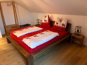 a large bed with red and white sheets and pillows at Schneekopfblick in Oberhof