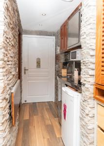 a kitchen with a white door and a stone wall at Cozy studio, beach and pool access with sea view in Marigot