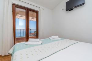 a white bedroom with a bed and a window at Apartments Kunac in Podgora