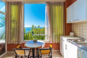 a kitchen with a table and chairs and a large window at Apartments Kunac in Podgora