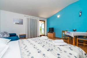 a bedroom with a large bed and a blue wall at Apartments Kunac in Podgora +50 photos